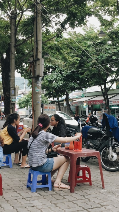三名妇女坐在停着的黑色摩托车旁